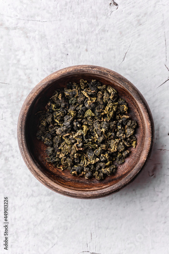 selective focus, natural green leaf tea. brewing in a wood bowl. vertical angle, macro. on a light background. for menus and cafes