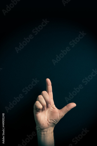Colour image of hand demonstrating ASL sign language letter L with empty copy space