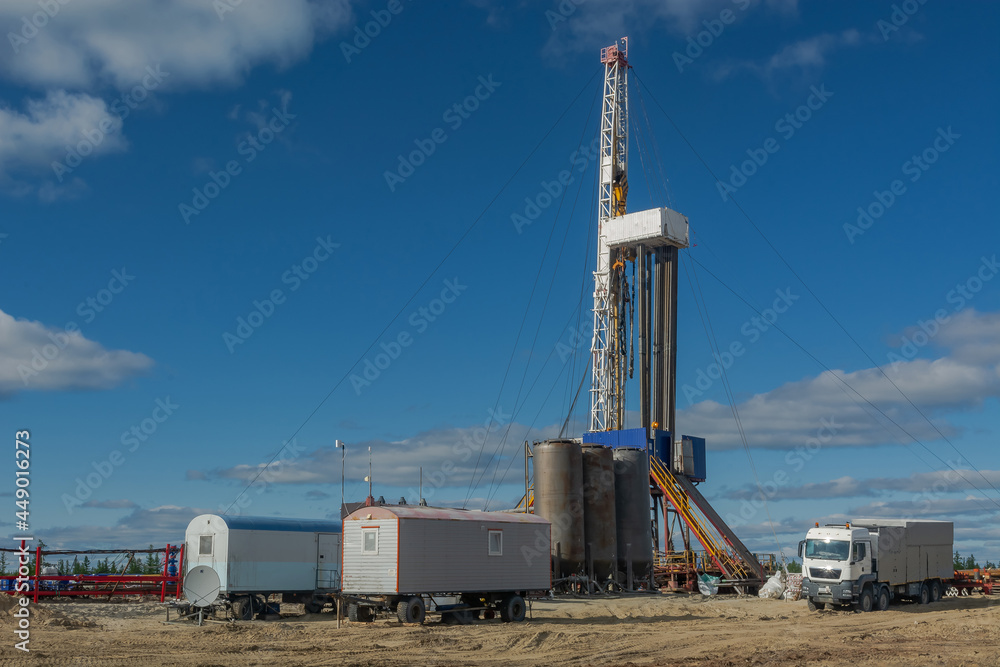 The drilling rig is included in the landscape of the oil and gas field. Infrastructure, communications and drilling equipment are visible. The drilling rig has equipment for well cementing The drilling rig is included in the landscape of the oil and gas field. Infrastructure, communications and drilling equipment are visible. The drilling rig has equipment for well cementing