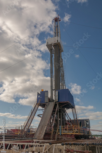 The design of a drilling rig for drilling wells in an oil and gas field in the far north. Oil rig with standing drill pipes and equipment against blue sky