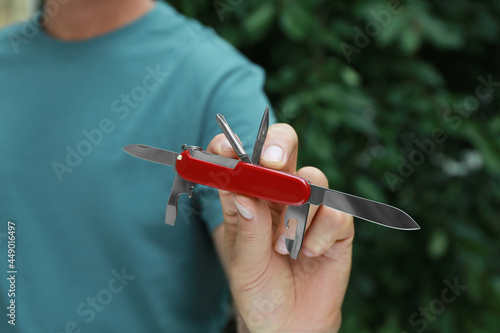Man holding compact portable multitool outdoors, closeup photo