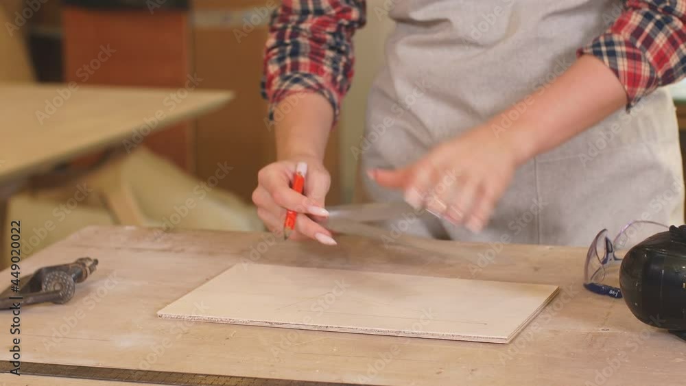 Hardworking caucasian woman make drawings before drilling and sawing, handmade wooden furniture, handicraft concept. Hardworking caucasian woman make drawings before drilling and sawing, handmade wooden furniture, handicraft concept.