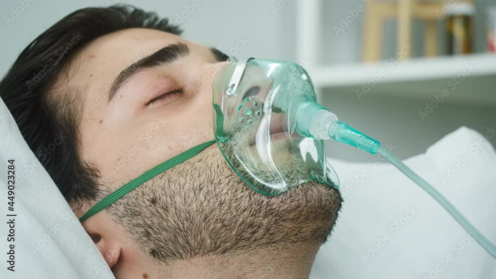 Sleeping patient lying with oxygen mask in reanimation, serious bad human condition with