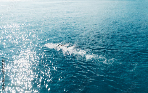 Man swims in the blue sea on sunny weather.