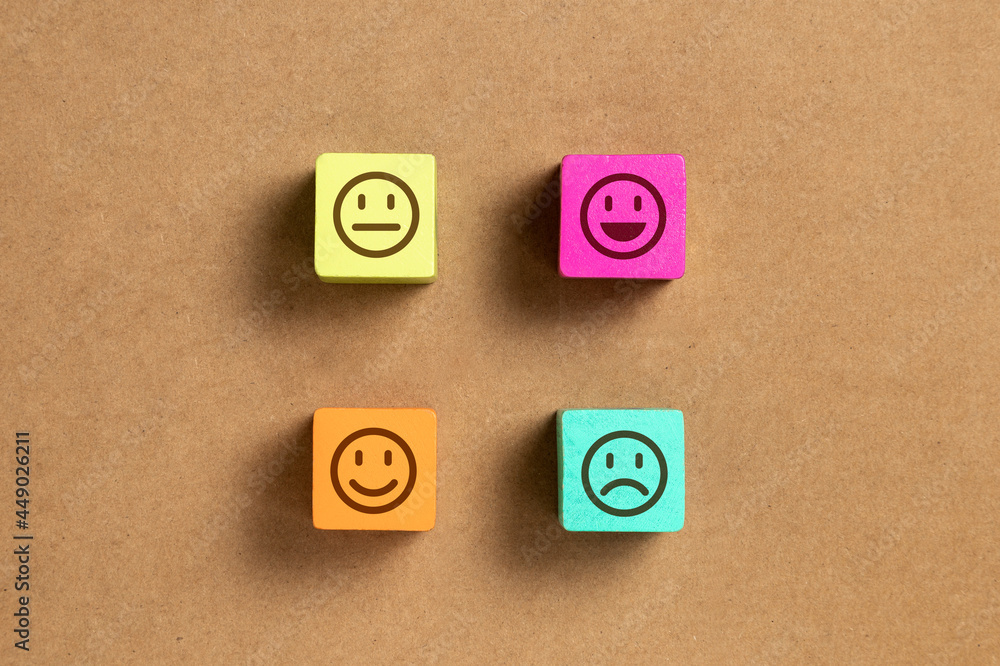 Emoticon faces in colors wooden blocks over brown wood paper. Service evaluation and satisfaction survey concepts. Angry, neutral, good mood and happy. Copy space. Flat lay photo Emoticon faces in colors wooden blocks over brown wood paper. Service evaluation and satisfaction survey concepts. Angry, neutral, good mood and happy. Copy space. Flat lay photo