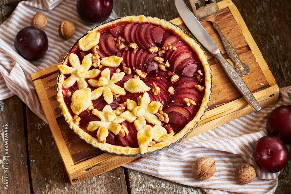 Pie with plum and nuts. Short crust pastry, chopped plums. Side view. Wooden background.