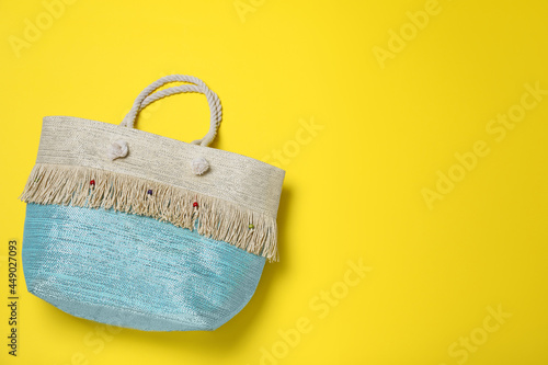 Stylish beach bag on yellow background, top view. Space for text