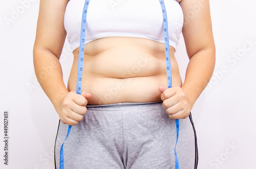 Beautiful fat woman with tape measure She uses her hand to squeeze the excess fat that is isolated on a white background. She wants to lose weight, the concept of surgery and break down fat under the