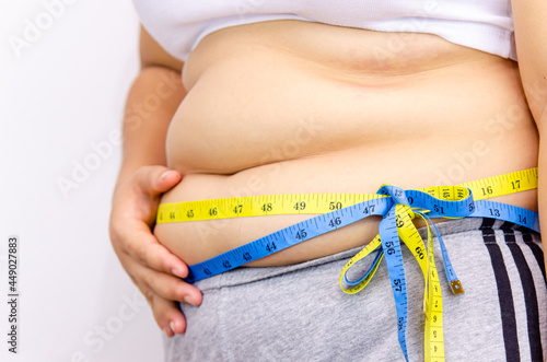 Beautiful fat woman with tape measure She uses her hand to squeeze the excess fat that is isolated on a white background. She wants to lose weight, the concept of surgery and break down fat under the