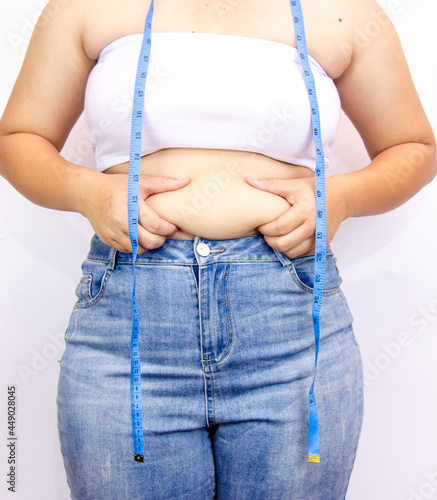 Beautiful fat woman with tape measure She uses her hand to squeeze the excess fat that is isolated on a white background. She wants to lose weight, the concept of surgery and break down fat under the