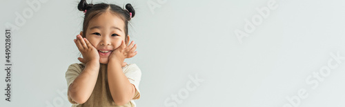 Foto happy asian toddler girl smiling isolated on grey, banner