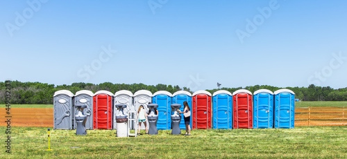Row of colorful mobility lavatory and washbasin, hygiene facility for people at outdoor event. Public temporary restroom at a park, attendees using amenity during festival, convenience and sanitation photo