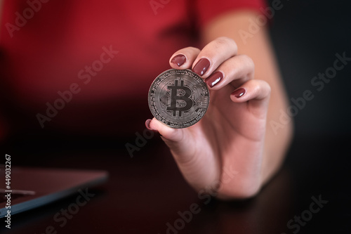 Closeup image of woman's hand holding and showing a bitcoin coin .