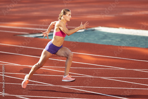 Track-and-field athletics. Young Caucasian woman, professional athlete, runner training at public stadium, sport court, outdoors. Concept of sport, achievment, motion.