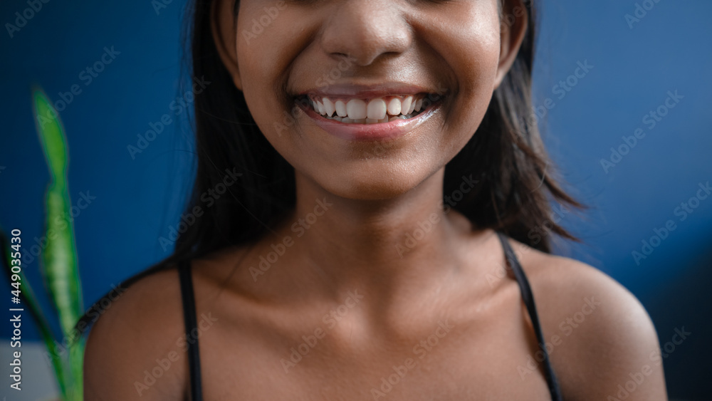 Close up of a cheerful dark-skinned girl in a beautiful smile with healthy white teeth and sweet pink lips | concept of oral hygiene Close up of a cheerful dark-skinned girl in a beautiful smile with healthy white teeth and sweet pink lips | concept of oral hygiene