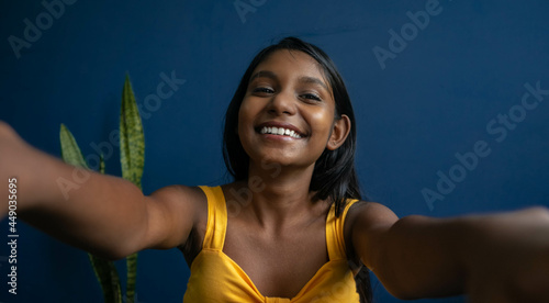Image of a cute young brunette teenage girl reaching hands forward catching something | smiling girl with friendly expression trying to greet someone with a warm hug