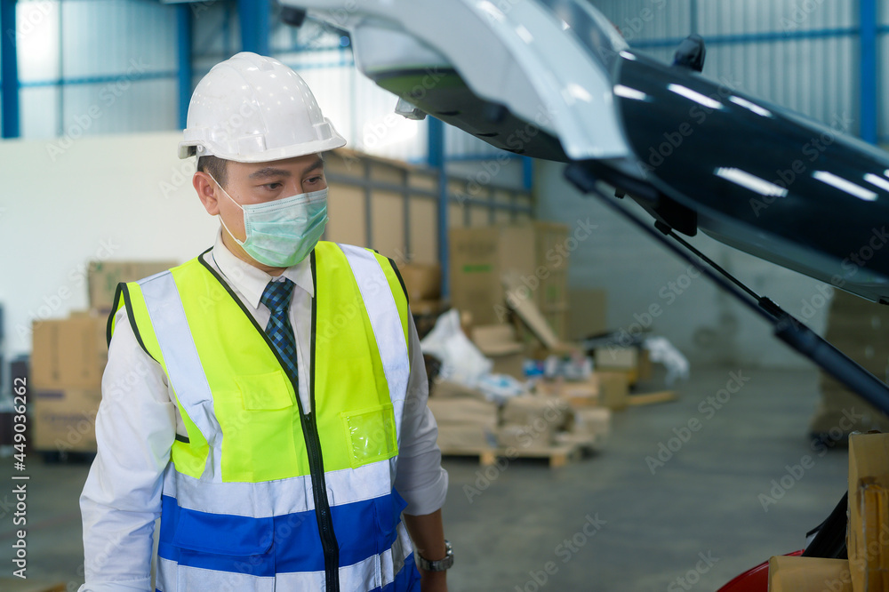 An engineering man wearing medical mask , protective helmet working in warehouse factory An engineering man wearing medical mask , protective helmet working in warehouse factory
