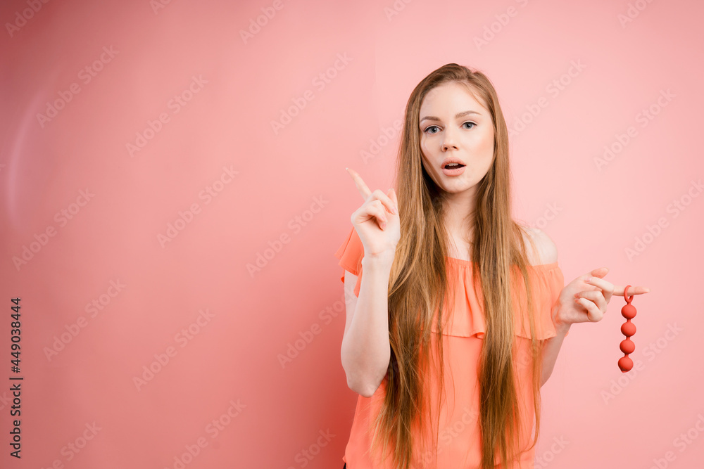 Woman with ginger hair holds dildo with open mouth and pointing her finger isolated on pink background. Sex toys Woman with ginger hair holds dildo with open mouth and pointing her finger isolated on pink background. Sex toys