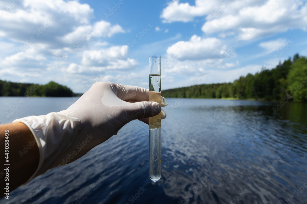 Scientist takes samples of dirty water from a pond. Hand is collects ...