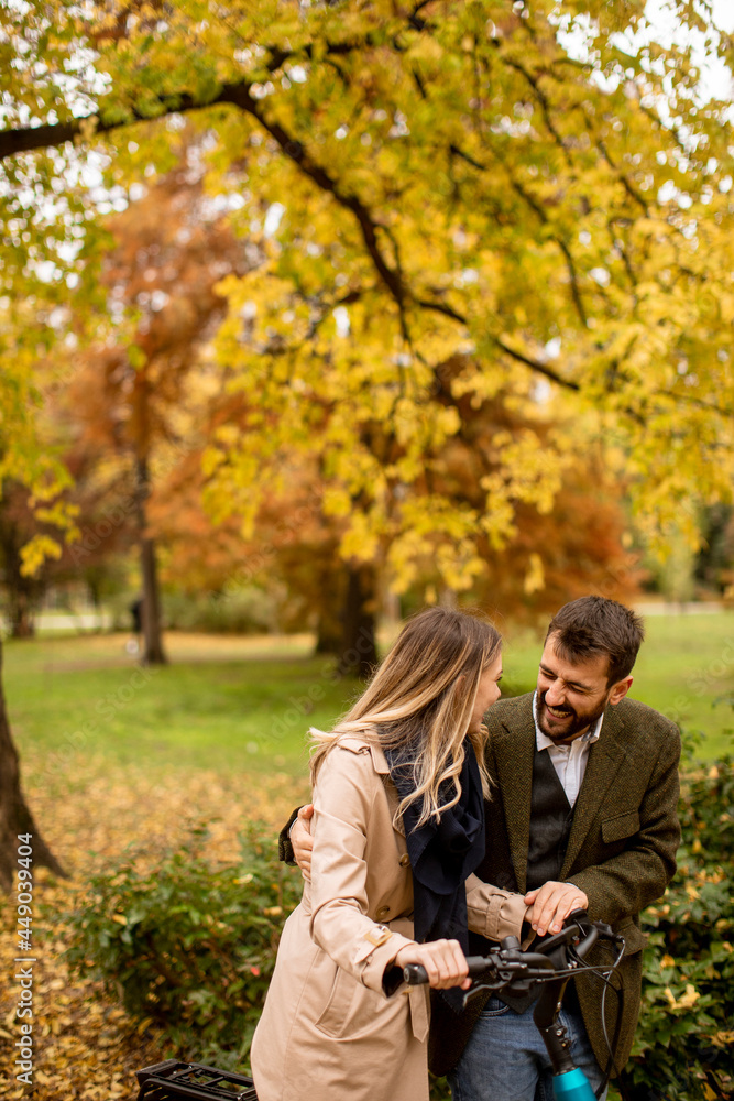 Young couple in the autumn park with electrical bicycle Young couple in the autumn park with electrical bicycle