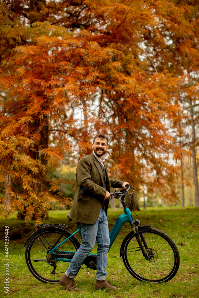 Fototapeta premium Handsome young man with electric bicycle in the autumn park