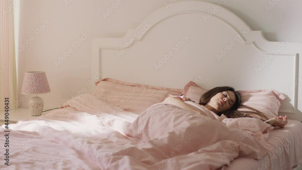 A further back angle of a beautiful brown haired woman sleeping in her cute pyjamas and duvet set A further back angle of a beautiful brown haired woman sleeping in her cute pyjamas and duvet set