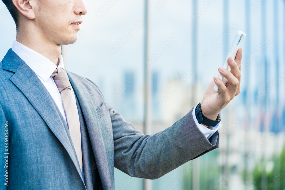 スマートフォンを持つスーツ姿の男性の手