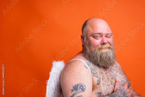 Fat doubter man with beard ,tattoos and wings acts like an angel