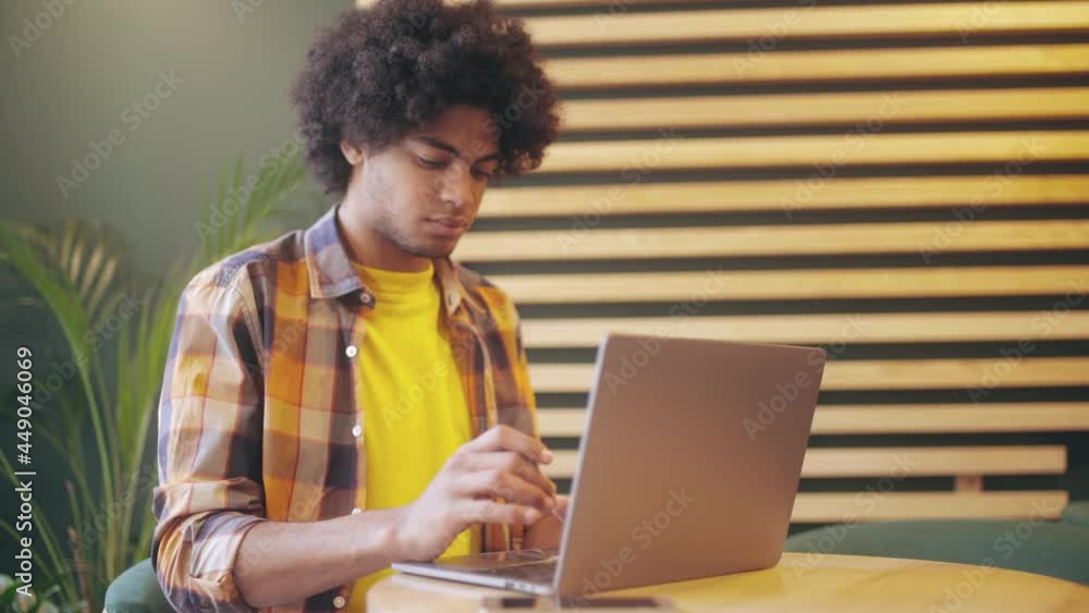 Biracial young man working on laptop in cafe, freelance job, distance education Biracial young man working on laptop in cafe, freelance job, distance education