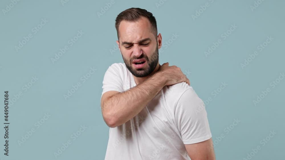 Sick ill young brunet man 20s wears white t-shirtfeels bad suffering from pain spasm back sprain or neck shoulder isolated on pastel light blue background. Healthy lifestyle disease treatment concept Sick ill young brunet man 20s wears white t-shirtfeels bad suffering from pain spasm back sprain or neck shoulder isolated on pastel light blue background. Healthy lifestyle disease treatment concept