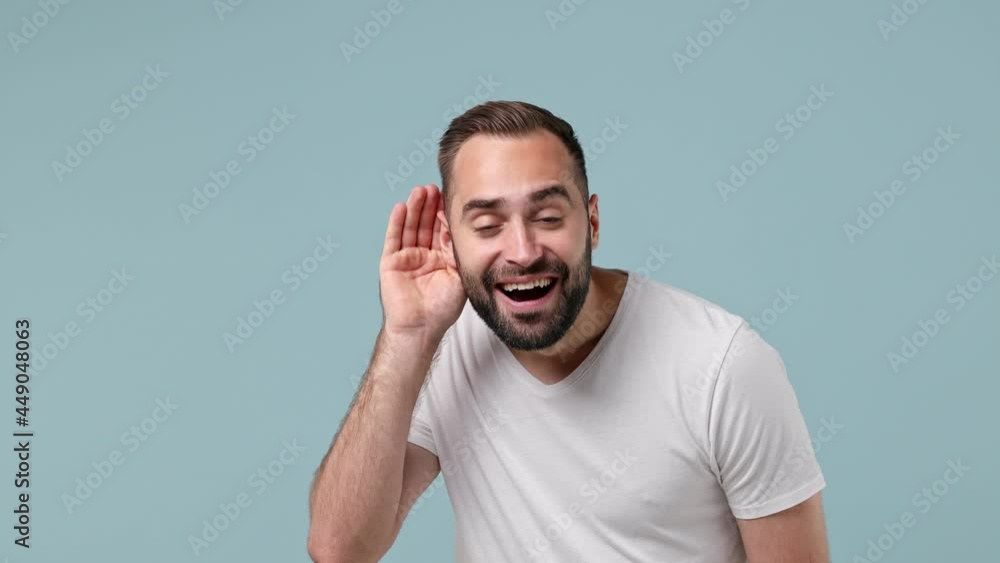 Curious nosy happy cool fascinating young brunet man 20s wears white t-shirt try to hear you overhear listening intently hot news show thumb up like gesture isolated on pastel light blue background Curious nosy happy cool fascinating young brunet man 20s wears white t-shirt try to hear you overhear listening intently hot news show thumb up like gesture isolated on pastel light blue background