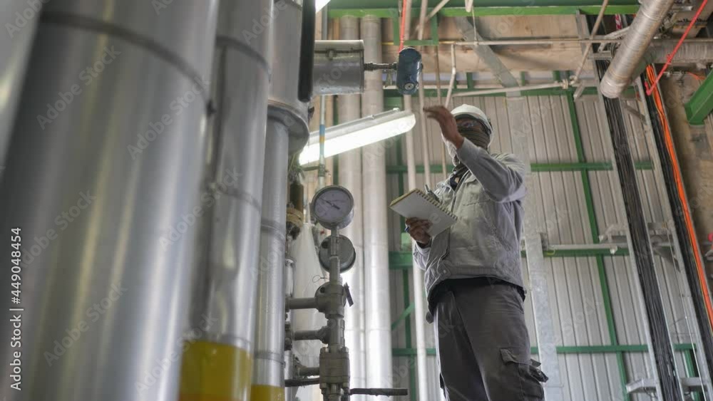 Industrial worker working in industrial plant, He visually checks plant equipment and record to a paper sheet Industrial worker working in industrial plant, He visually checks plant equipment and record to a paper sheet