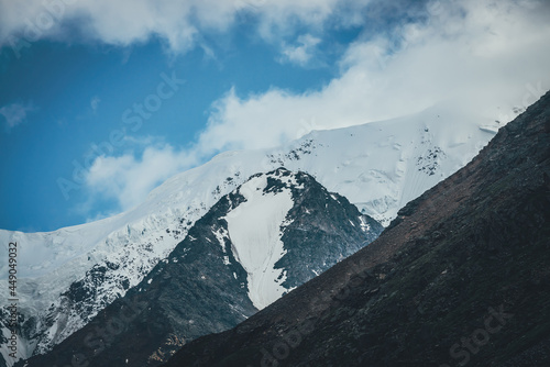 Awesome mountain landscape with great snowy mountain top. Atmospheric scenery with snow-white high mountain with glacier. Big mountains with snow. Scenic view to giant black rocks with white snow.