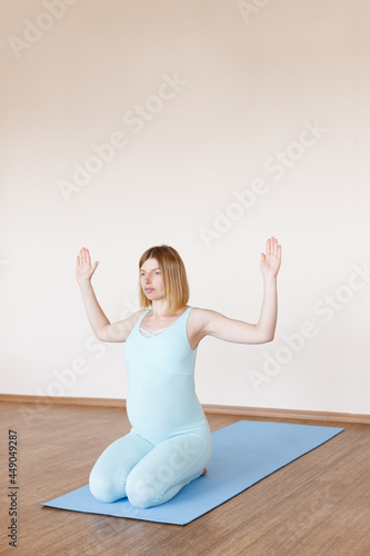 pregnant woman sitting on a mat practicing yoga in the studio