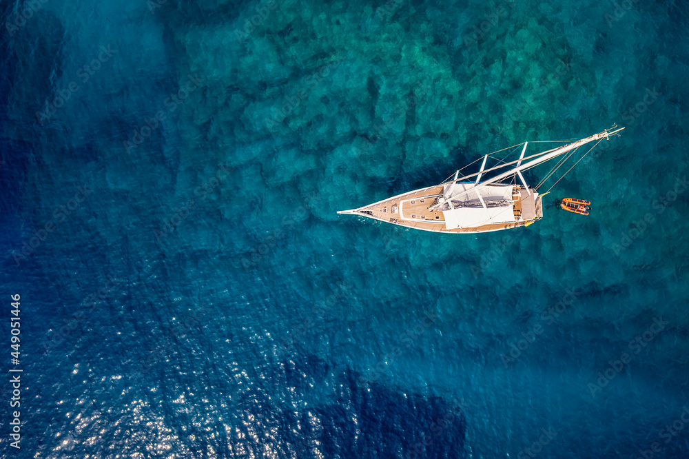 Foto Stock Aerial top down view to a sailing boat over the turquoise and  emerald shining, mediterranean sea | Adobe Stock