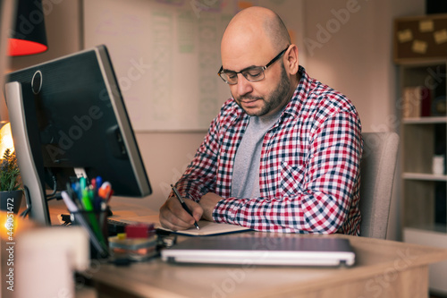Male freelancer taking notes while having online meeting