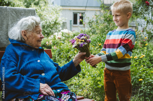Reunited, family, togetherness, relationships, meeting, embracing. Grandson visit grandmother gives flowers after long break due to coronavirus quarantine