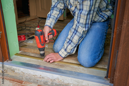 man is making a threshold on the floor,Installation of self-adhesive threshold when docking floor coverings