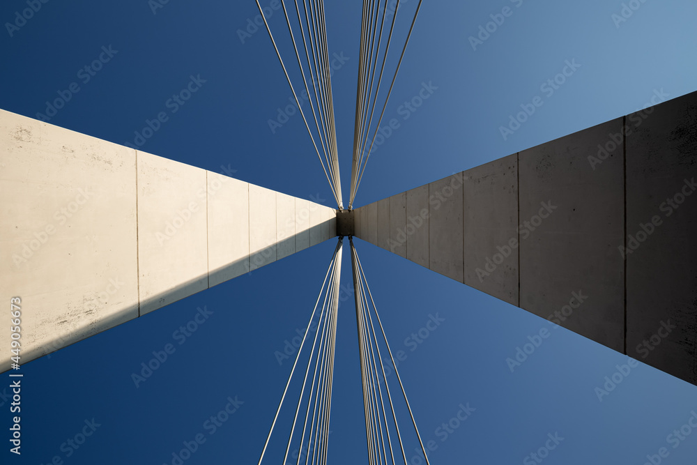 Obraz premium Minimalist abstract architecture shot featuring a white concrete pillar of a suspension bridge with two bunches of suspension cables against a clear blue sky