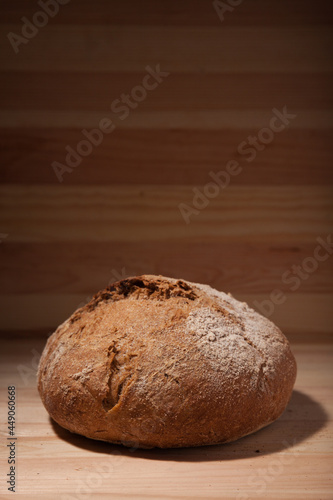 Handmade fresh wheat bread on wooden background in the contrast light. vertical frame side view with space area for text or design