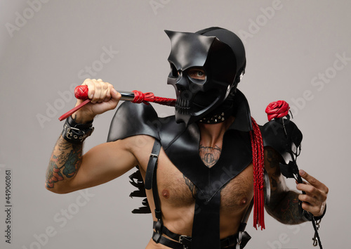 Canvastavla a man in bdsm wearing a skull demon mask with a whip and a rose flower, dressed
