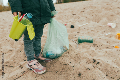 Kid picking up plastic garbage on the sand beach © lithiumphoto
