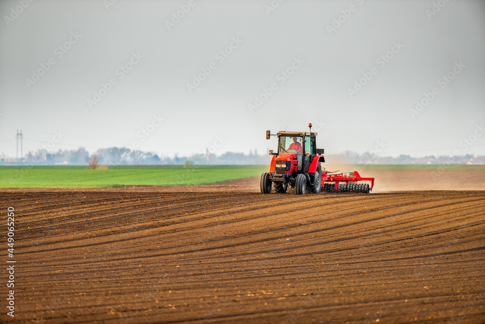 Obraz premium Farmer in tractor preparing land with seedbed cultivator as part of pre seeding activities in early spring season of agricultural works at farmlands.
