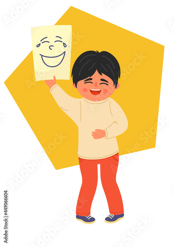 Laughing boy holds piece of paper with drawn laughing face. Children emotional development, empathy, positive emotion concepts. 