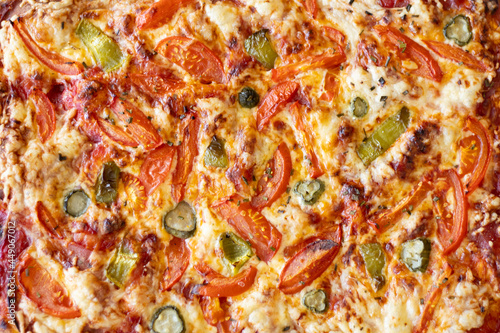 Delicious pizza topping background texture with tomatoes, paprika, cucumbers, salami and melted mozzarella cheese, viewed from above. Top down view.