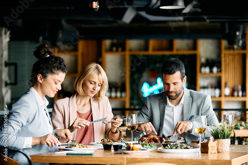 Group of young business people eat on lunch break in restaurant.