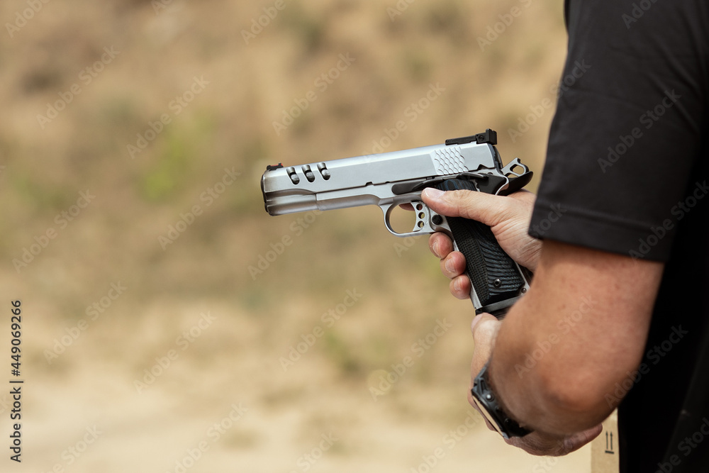 Man in tactical clothes shooting from a pistol, reloading the gun and aiming at the target in the open-door Shooting range Man in tactical clothes shooting from a pistol, reloading the gun and aiming at the target in the open-door Shooting range
