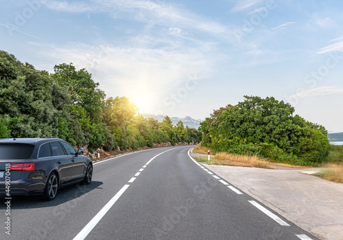 Black car on a scenic road. Car on the road surrounded by a magnificent natural landscape.