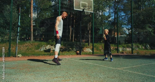 Basketball players exercising warming up before workout. Sportive family father and son training on basketball court 