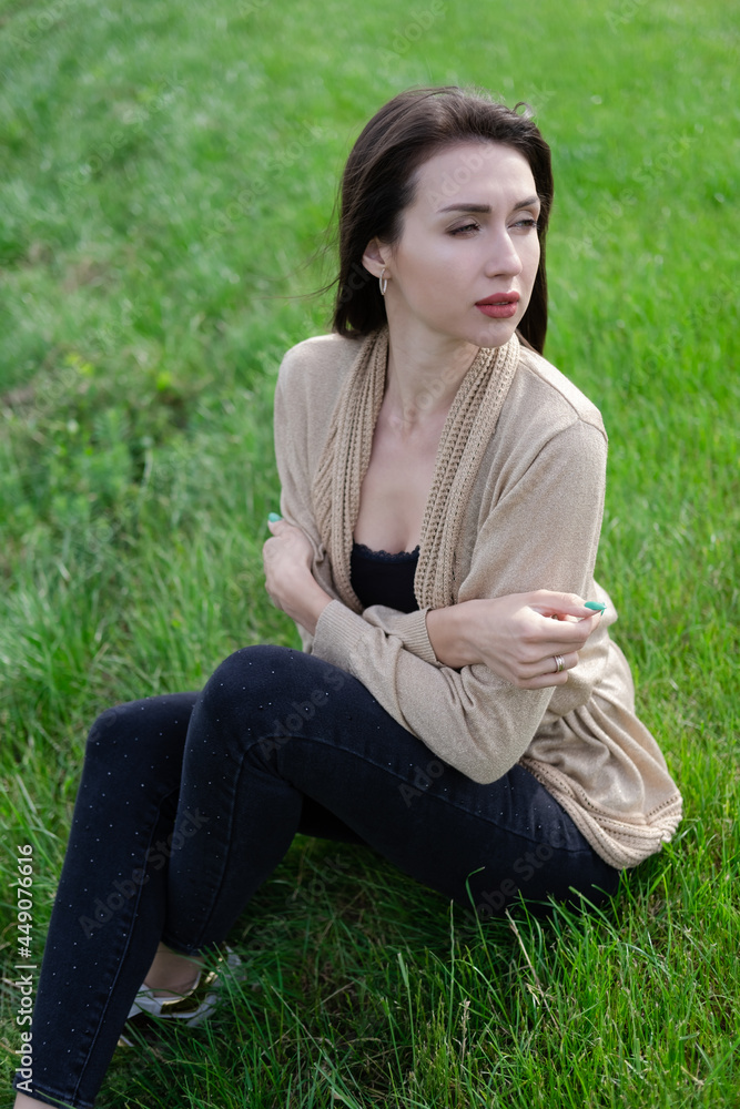 beautiful brunette woman sitting on green grass. beautiful brunette woman sitting on green grass.